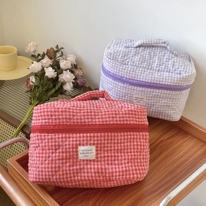 Detailed macro view of quilted berry checkered cosmetic bag with handle and zipper