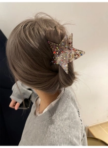 Close-up of a star-shaped hair claw with colorful sequins on a model's hairstyle