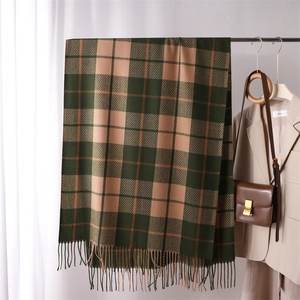Detail of dark green and khaki plaid cashmere scarf with tassels in a minimalist setting