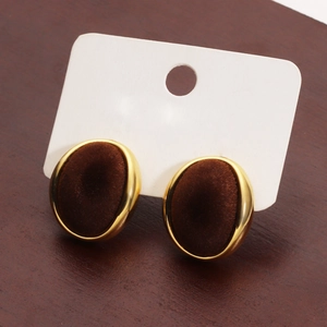 Detail of oval velvet earrings with gold plated frame on a wooden surface