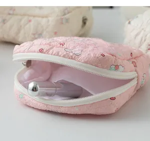 Detail of pink quilted sanitary pouch opening showing storage capacity for small items