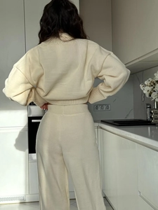 Detail der Rückansicht, die den Fall des cremefarbenen Strickpullovers und der weiten Hose zeigt