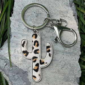 Close-up of leopard print cactus keychain with metal ring on natural stone background