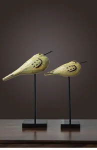 Close-up of set of 2 yellow-green cracked glaze bird figurines with black metal stands
