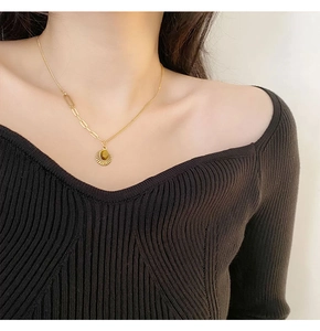 Close-up of golden sun pendant with tiger eye stone and clip chain on neck
