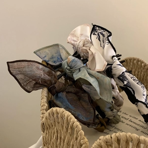 Close-up of stylish silk fabric bow headbands with blue and brown patterns in a basket