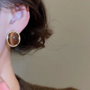 Close-up of model wearing oval tiger eye earrings with 18k gold plated finish