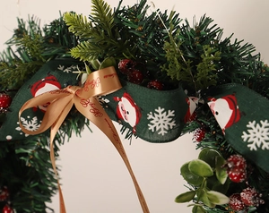 Macro detail of Christmas wreath with red berries, pine needles and Merry Christmas ribbons