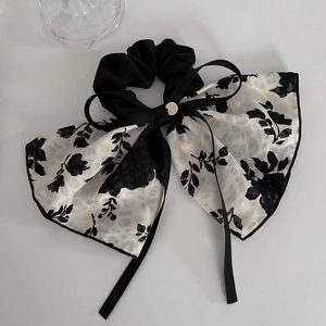 Detail of floral ribbon bow scrunchie with translucent fabric and gold pendant