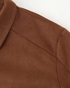 Gros plan de l'épaule d'une veste en daim marron avec surpiqûres et texture douce