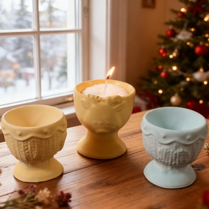 Detail of Christmas elk embossed candle holders with woven texture and burning wax