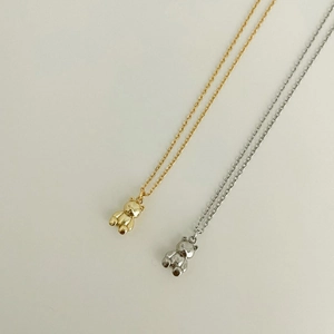 Macro detail of 3D carved bear pendant necklaces in gold and silver metallic finishes