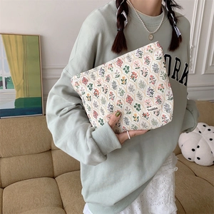 Detailed shot of a floral cotton makeup bag held by a model in a cozy home setting