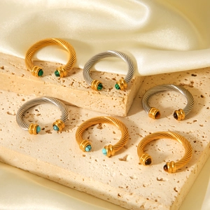 Gros plan de bagues torsadées avec malachite et oeil de tigre sur des pierres texturées