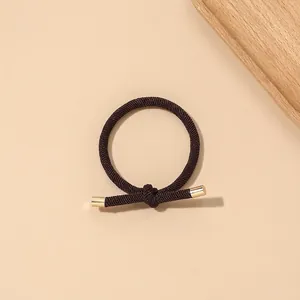 Close-up of brown braided elastic hair tie with stylish gold metal tube accents