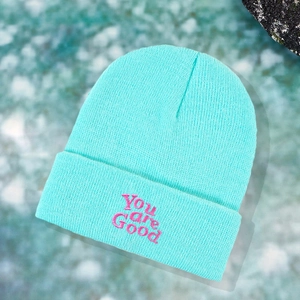 Detail shot of the mint green beanie featuring pink You are Good embroidery texture