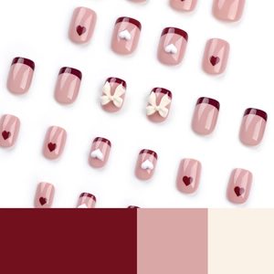 Short French press-on nails with red hearts and cream bows on pink and white tips