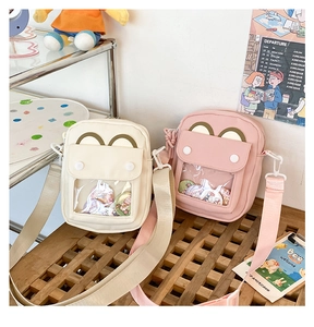 Detail showing two canvas crossbody bags with transparent window display and cute pins