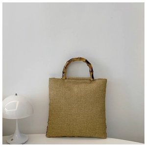 Linen texture handbag with natural bamboo handle displayed next to a white mushroom lamp