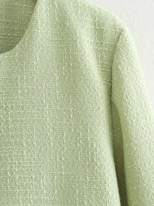 Close-up detail of light green tweed fabric texture on shoulder and collar area