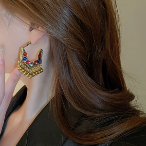 Close-up of bohemian hollow teardrop tassel earrings with colorful gems on a model