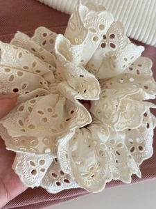 Détail d'un chouchou en dentelle crème avec broderie ajourée délicate et volants superposés