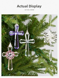 Macro shot of clear acrylic cross and snowflake ornaments hanging on a Christmas tree branch