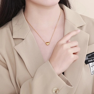 Close-up of a minimalist gold heart pendant necklace on a model's neck for a chic look