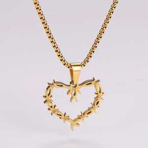 Detail of golden heart pendant featuring thorn design and bird motif on a box chain