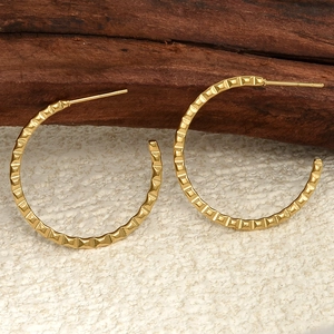 Macro detail of golden textured C-shape hoop earrings showing square grid pattern finish