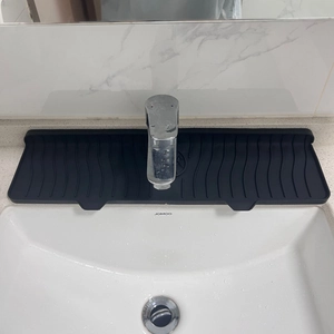Detail of black silicone kitchen faucet splash pad with wave drainage texture on sink