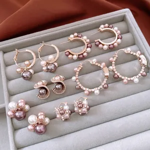Collection of pearl stud and hoop earrings with zircon accents on gold velvet display