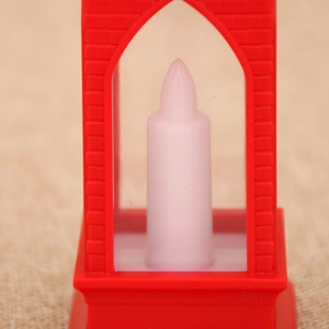 Macro detail of red Christmas lantern with arched window and white flameless candle