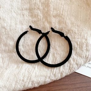 Macro shot of large black velvet flocked hoop earrings with minimalist vintage texture