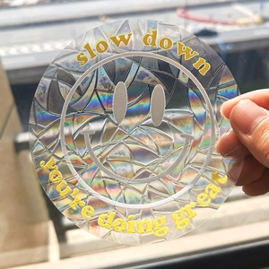 Close-up of holographic suncatcher sticker with smiley face and slow down text detail