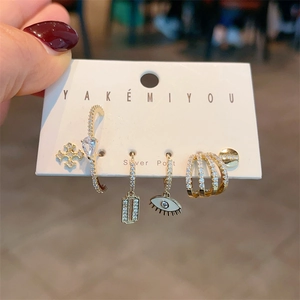 Detailed view of 5-piece earring set with cross, evil eye, and zircon charms