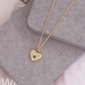Irregular golden heart necklace with a blue gemstone on a minimalist stone base