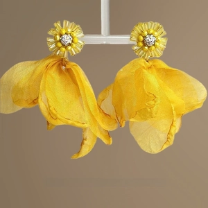 Macro view of floral tassel earring featuring yellow fabric petals and beaded center detail