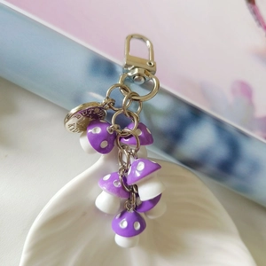 Detail of five purple mushroom charms with white dots on a silver metal keychain