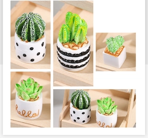 Close-up of four mini faux succulents in white ceramic pots on a wooden shelf