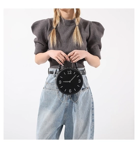Vue détaillée d'un sac à main rond noir en forme d'horloge avec chaîne métallique chic