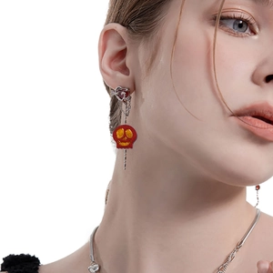 Detalle de pendiente de Halloween con calavera de esmalte rojo y botón de corazón
