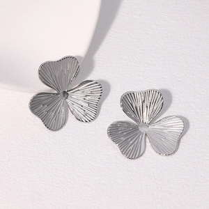 Macro shot of silver clover flower earrings with detailed striped metal texture