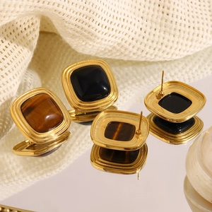 Macro shot of gold-plated square studs with tiger eye stone and black enamel inlay