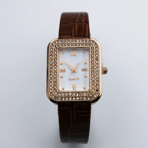 Close-up of a square rose gold watch case with crystal bezel and brown leather strap