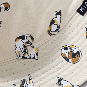Close-up of beige canvas bucket hat showing fine stitching and cute cat print detail