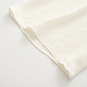 Close-up of cream white fabric showing detailed seersucker texture and sewing quality