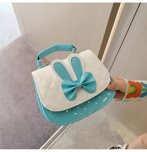 Close-up of children's handbag featuring a white quilted flap with cute bunny ears and bow