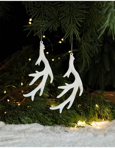 White reindeer antler ornaments with glitter on green pine branches for Christmas decor