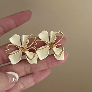 Close-up of double-layer hollow floral stud earrings with white petals and gold center